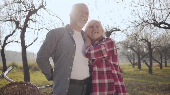 Portrait of a Happy Senior Caucasian Couple Standing in Sunlight in the Foggy Park and Talking