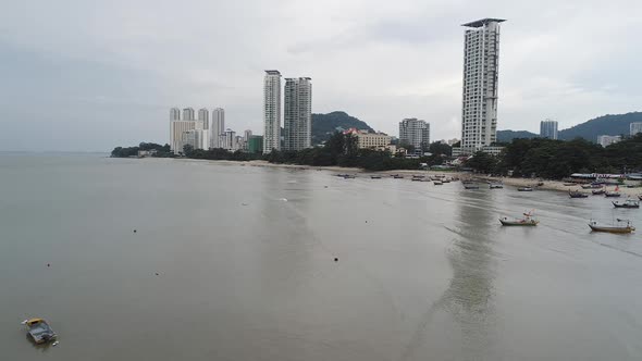 Forward flight clip of a shoreline with boats in Penang Malaysia