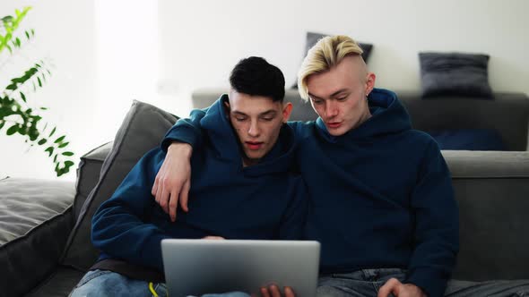 Loving Gay Couple Spend Time at Home Watching Movie Togather on Laptop