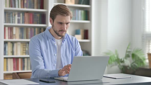 Man Thinking While Working on Laptop in Office