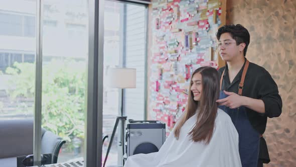 Asian professional male Hairdresser or hairstylist combing and using scissors cutting woman's hair.