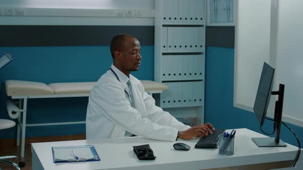 Portrait of African American Doctor Using Computer in Cabinet