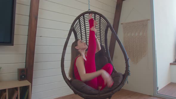 Sporty Woman Sitting in Heron Pose in Swing Chair