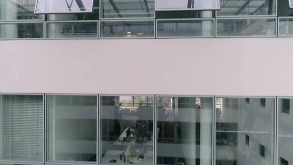 Windows and offices of a business building. Atrium. Camera descending.