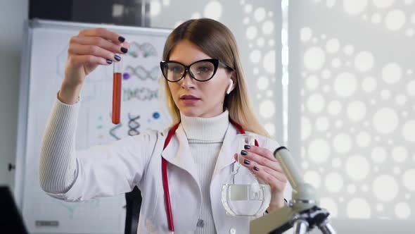 Female Doctor in Glasses wich Uses Test Tubes with Liguid and Doing Medical Researchh