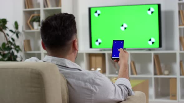 Man Using Smartphone and Watching TV with Green Screen