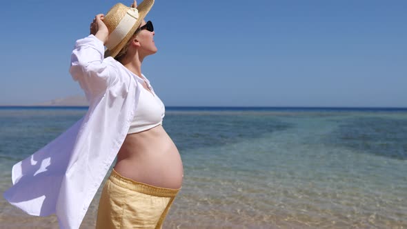 Young Pregnant Woman Standing At Beach By The Sea