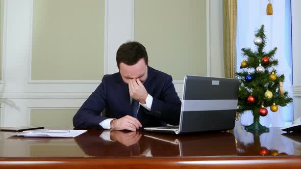 Depressed Young Businessman Grabs His Face and Cries Suggestively Because He Is Alone at Christmas