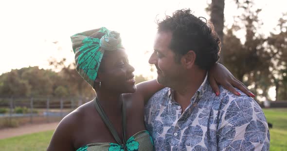 Multiracial couple having tender moment at city park - Love concept