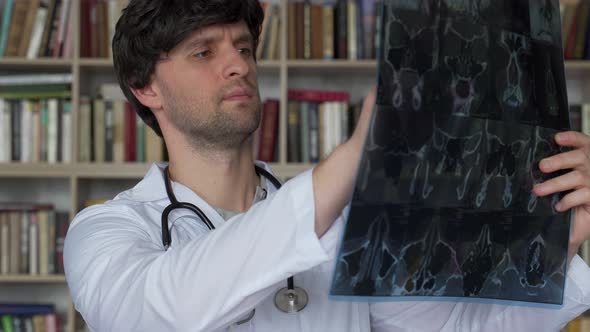 Man Doctor Looks at an Xray of a Patient in the Clinic
