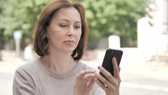 Old Woman Using Smartphone Standing Outdoor on Footpath