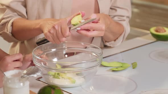 Cutting Avocado In Slices To Bowl
