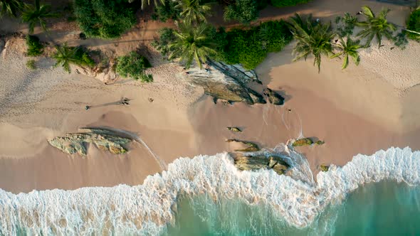 Ocean Waves Crash Against Stony Rocks During Sunset on the Island of Sri Lanka. Aerial View