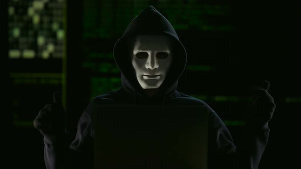 Hacker in mask and gloves breaking government servers