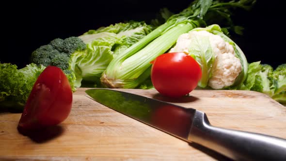 Slow Motion Video of Tomato Falling on Sharp Chef Knife Lying on Wooden Cutting Board and Splitting