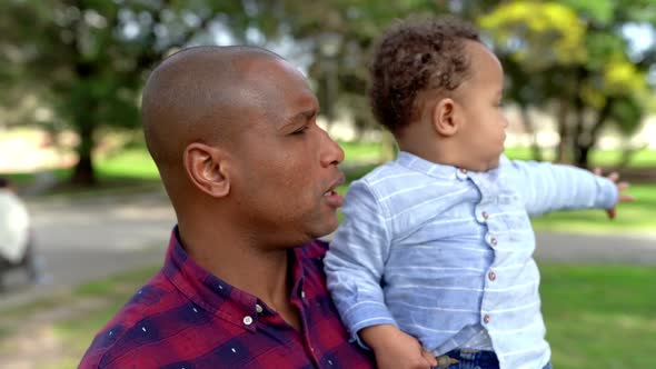 African American Bald Father Holding Son and Talking with Him