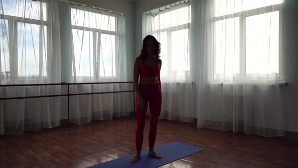 A Young Woman Fitness Instructor in Red Sportswear Leggings and Top Stretching in the Gym Before Her