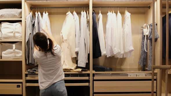 A Young Girl Looks Through Her Clothes on a Hanger to Choose What She Should Wear to a Meeting