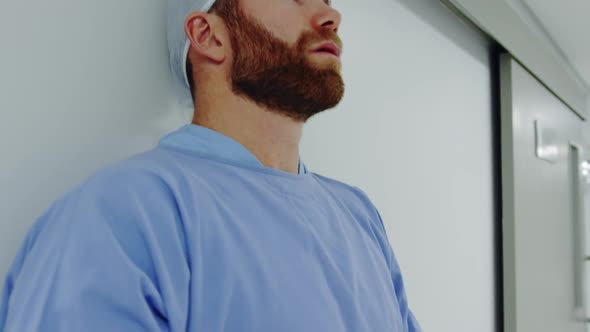 Close-up of worried Caucasian male doctor standing in the corridor