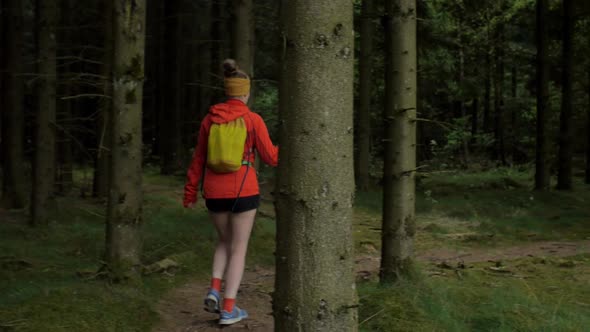 female hiker walking on a trail in the woods, camera pan from left to right to follow the movement,