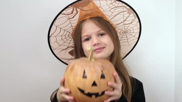 Little Girl in Witch Costume is Dancing with Pumpkin