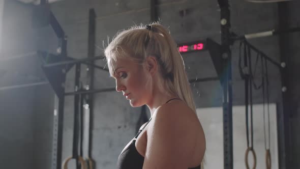 Sportswoman Applying Chalk Powder to Hands in Gym alt