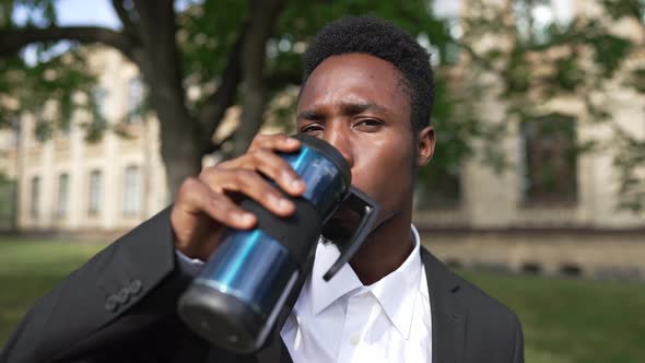 Young African American Man Drinking Morning Coffee From Thermos Looking at Camera with Confident