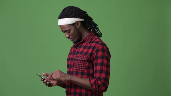 Young Handsome African Man with Dreadlocks Against Green Background