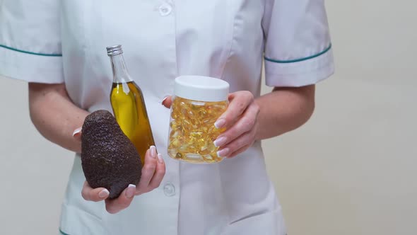 Nutritionist Doctor Holding Avocado Fruit and Jar of Medicine or Omega 3 Capsules and Bottle of Oil