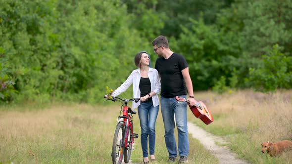 Young happy couple walking holding bicycles in the park