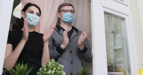 Young People in Medical Masked Applauds in Window in Support of People Who Fight Against Coronavirus