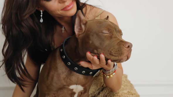 Chic Woman Kissing Her American Pit Bull Terrier and Smiling