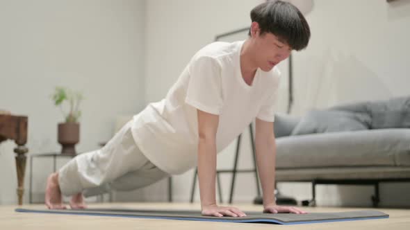 Tired Asian Man Doing Pushups on Yoga Mat at Home