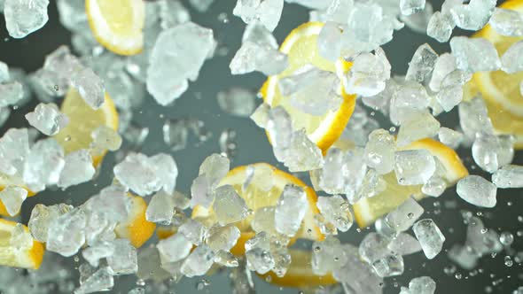 Super Slow Motion Shot of Flying Fresh Lemon Slices and Crushed Ice on Grey Background at 1000 Fps