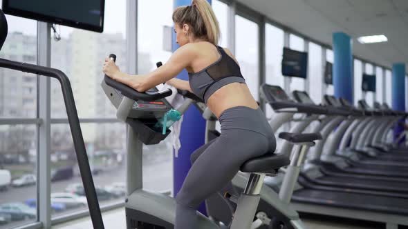 Young woman on bike at gym exercising