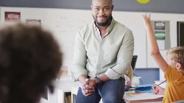 Video of happy african american male teacher during lesson with class of diverse pupils