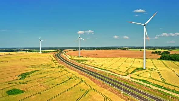 Wind turbines, highway and golden fields in summer, aerial view