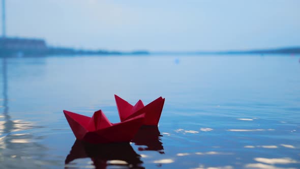 Womans Hand Putting Paper Boat on the Water