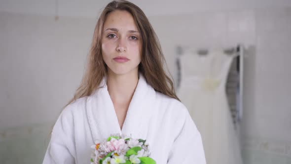 Sad Frustrated Depressed Young Bride Standing with Bouquet in Bathroom in the Morning Shaking Head