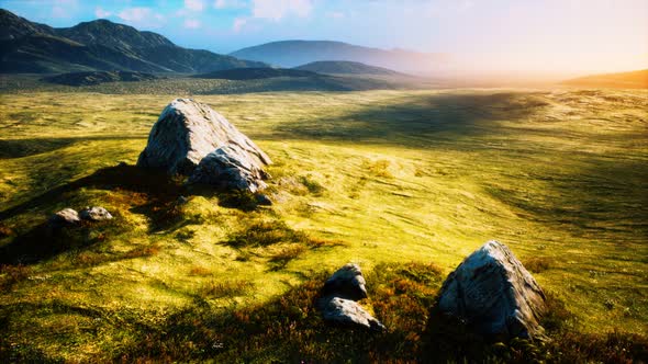 Meadow with Huge Stones Among the Grass on the Hillside at Sunset