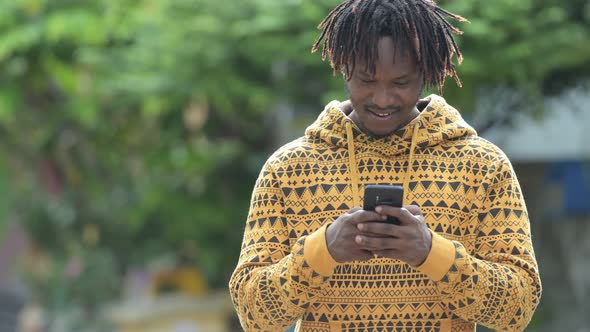 Young Handsome African Man Using Phone in the Streets Outdoors