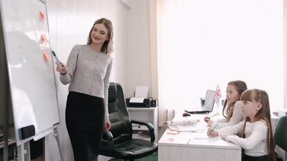 Teacher Teaches Two Schoolgirls in the Classroom