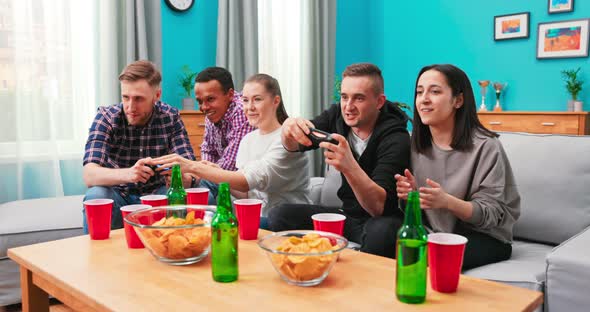 Cheerful Mixed Races Friends Resting in Room Sitting on Sfoa Playing Video Games Using Joystick