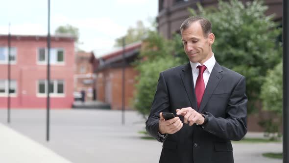 Businessman Celebrating Successful Results on Smartphone