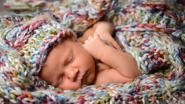 Newborn Baby Sleeps in a Knitted Scarf