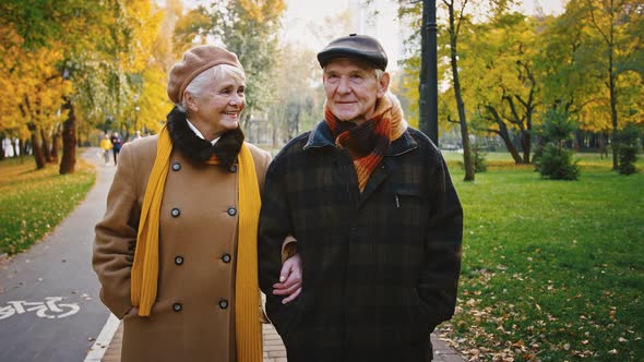 Aged Pair Grayhaired Grandparents in Elegant Outerwear are Talking and Smiling During Romantic Walk