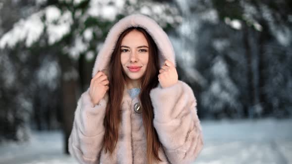 Joyful Woman Walking at Winter Forest Posing in Hood Fur Coat