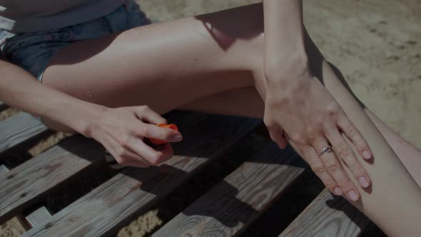 Woman Applying Sunscreen Lotion Tan Oil Spray on Legs and Body