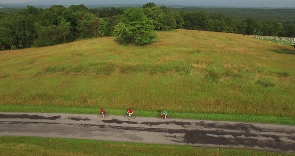 Aerial views of family bicycling along pastoral country roads.