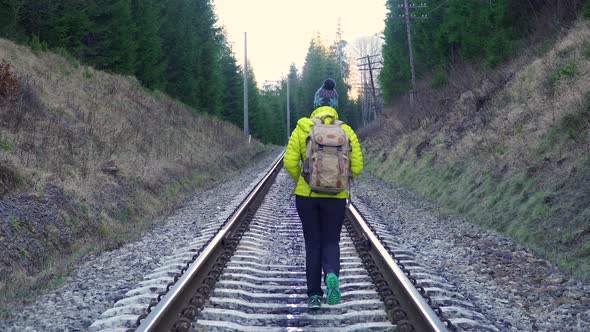 A Woman with a Backpack Walks on the Railway